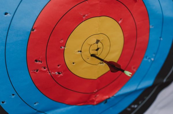 Close-up of a target in archery with a single arrow hitting the bullseye, showcasing precision and skill.