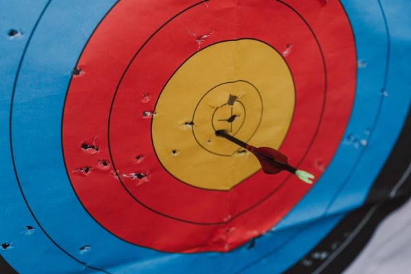 Close-up of a target in archery with a single arrow hitting the bullseye, showcasing precision and skill.